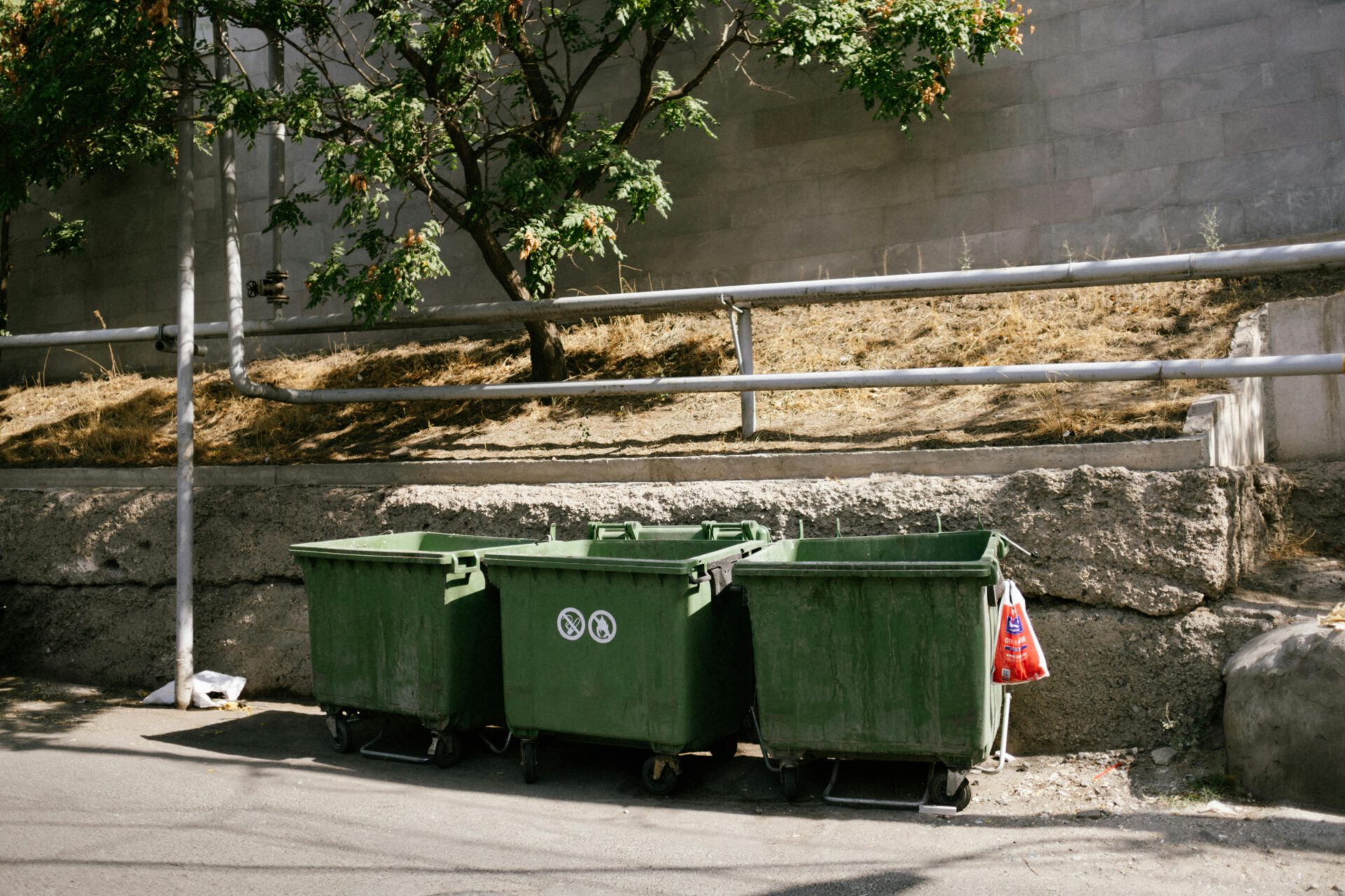 Green recycling bins on a sunny street in Yerevan, Armenia, promoting environmental awareness.