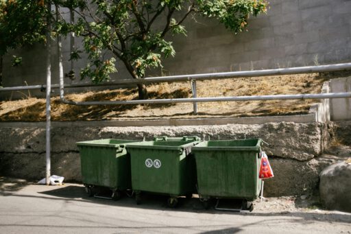 Green recycling bins on a sunny street in Yerevan, Armenia, promoting environmental awareness.