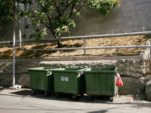Green recycling bins on a sunny street in Yerevan, Armenia, promoting environmental awareness.