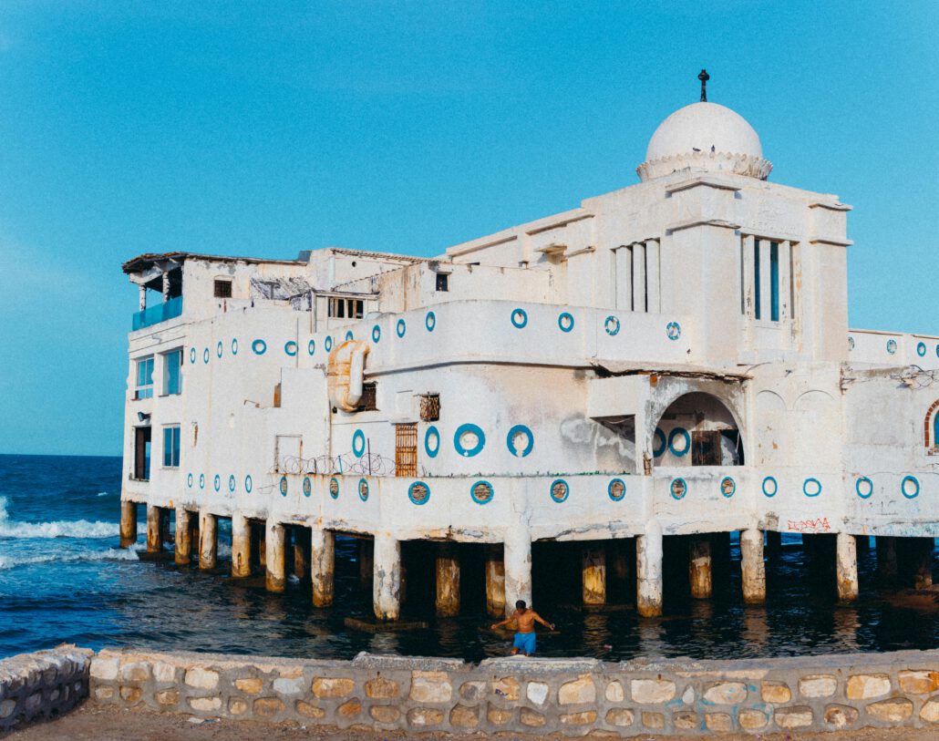 Historic building by the sea with vibrant blue accents in La Marsa, Tunis. Captivating sky and serene waterscape.
